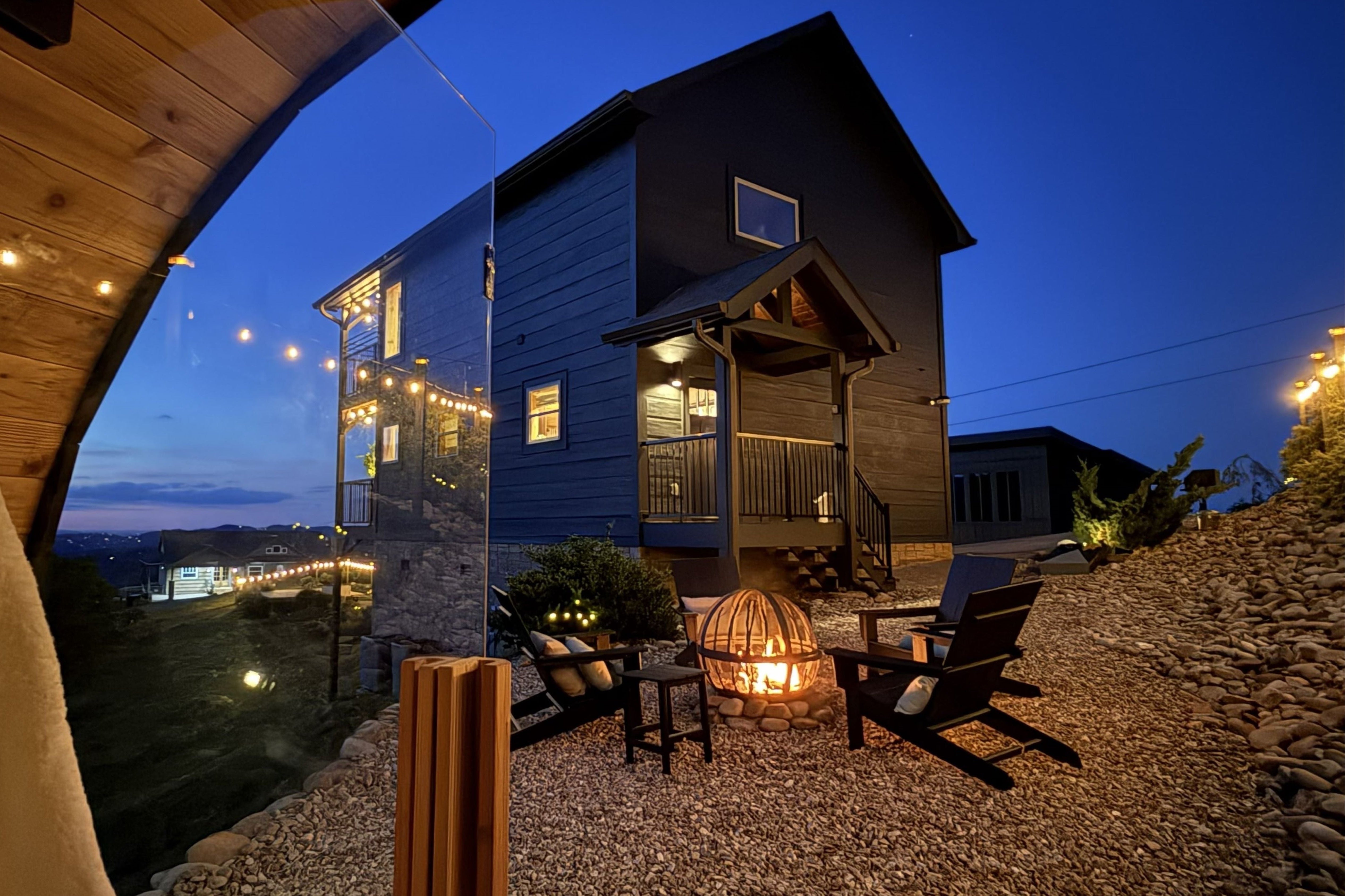 Evening view of a wooden cabin with outdoor seating area and illuminated windows at Everwild Stays